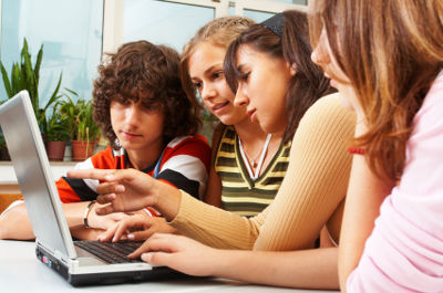 Group of young students working on laptop computer in classroom